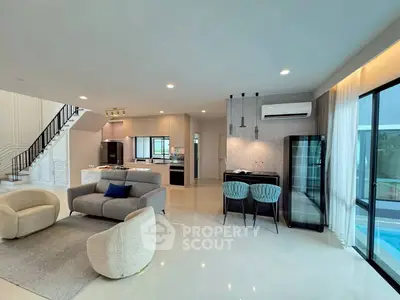 Spacious modern living room with open kitchen and pool view, featuring elegant furniture and sleek design.