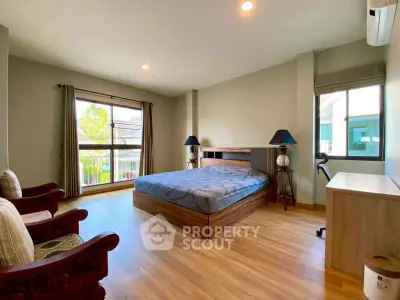 Spacious bedroom with large windows and elegant wooden flooring