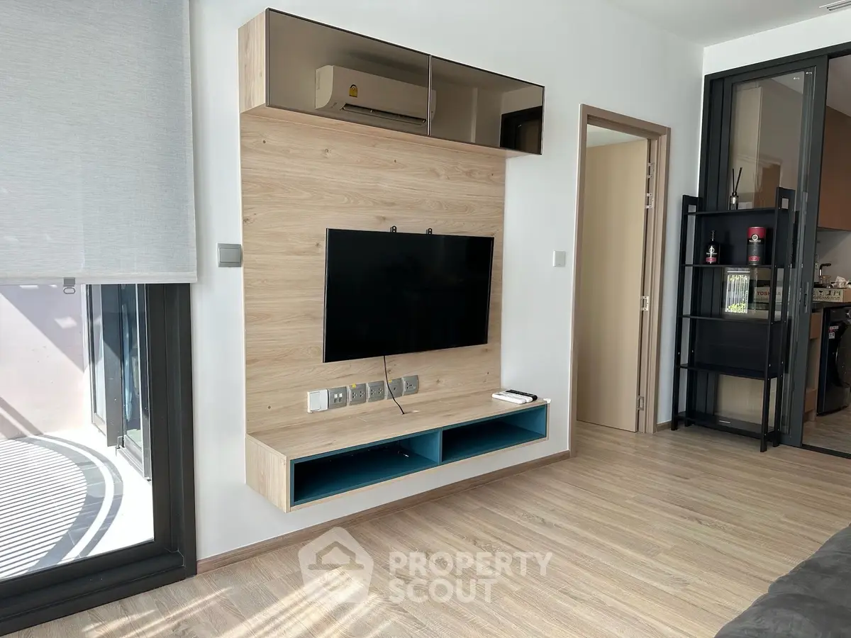Modern living room with sleek TV setup and large window for natural light.