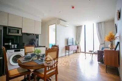 Modern open-plan living room with dining area and kitchen, featuring wooden flooring and natural light.