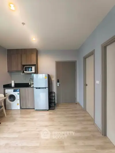Modern kitchen with fridge, microwave, and washing machine in a cozy apartment.