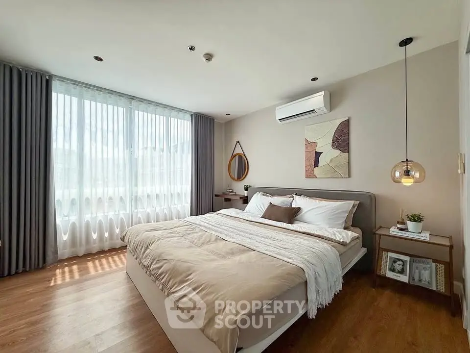 Elegant bedroom with modern decor, large window, and cozy ambiance in a stylish apartment.