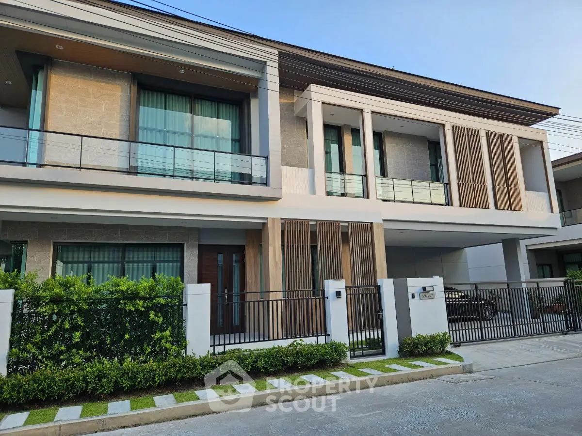 Modern two-story house with large windows and stylish facade in a serene neighborhood.