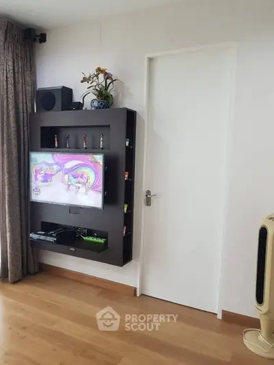Modern living room with wall-mounted TV and sleek wooden flooring.