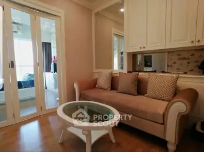 Charming living room with elegant sofa and glass coffee table, featuring sliding doors to a bright adjoining room.