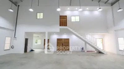 Spacious industrial-style interior with high ceilings and modern staircase