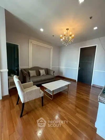Elegant living room with hardwood floors, chandelier, and stylish furniture in a modern apartment.