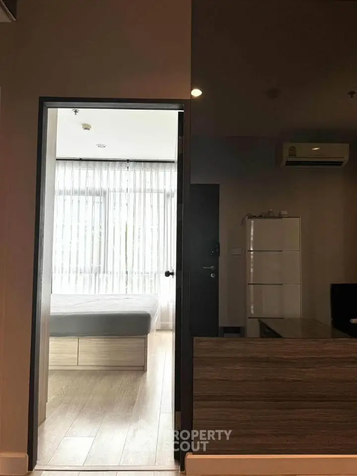 Modern apartment interior with bedroom and living area, featuring sleek furniture and natural light.