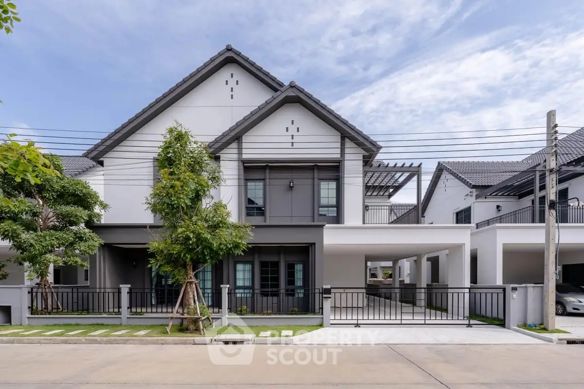 Modern two-story house with sleek design and spacious driveway in a suburban neighborhood.