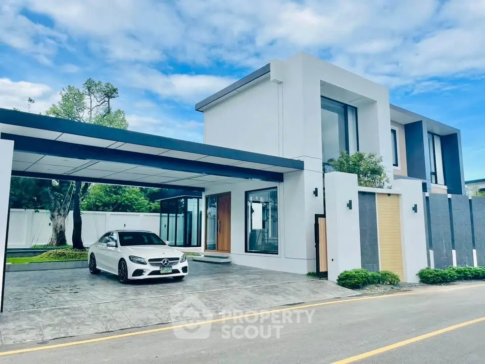 Modern luxury home with sleek design and spacious driveway featuring a stylish carport.