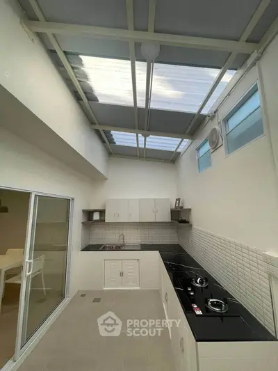 Modern kitchen with skylight and sleek black countertops in a contemporary home.