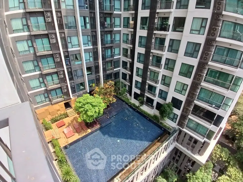 Stunning aerial view of modern apartment complex with luxurious pool and lush greenery.