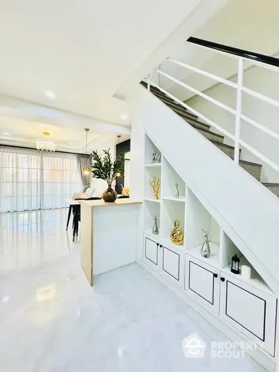 Luxurious open-plan living space with gleaming white floors, modern staircase, and elegant decor, perfect for sophisticated urban living.