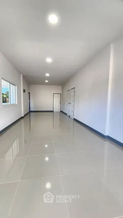 Spacious empty room with glossy tiled flooring and bright lighting