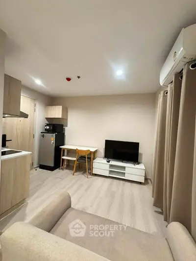 Modern living room with cozy furniture and sleek kitchen area in open layout apartment.