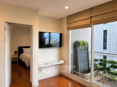 Modern bedroom with wall-mounted TV and balcony view in urban apartment