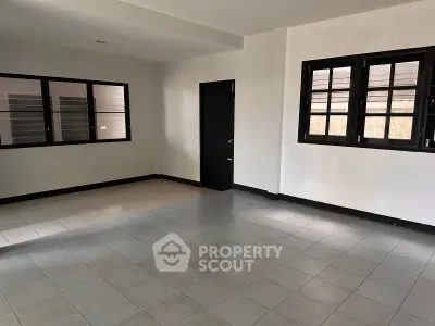Spacious empty room with tiled flooring and large windows, ideal for customization.