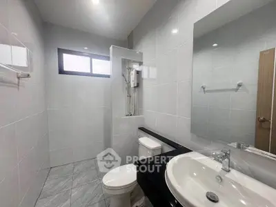 Modern bathroom with sleek fixtures and large mirror in a bright, tiled space.