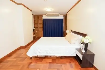 Spacious bedroom with wooden flooring and elegant decor in a modern apartment.