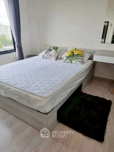 Modern bedroom with stylish bed and natural light from large window.