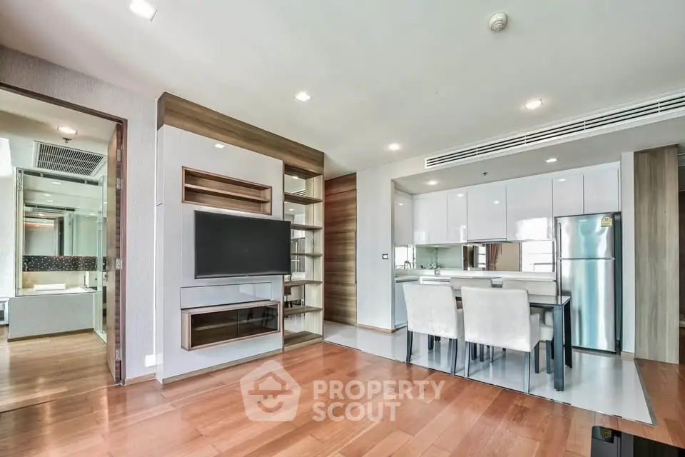 Modern open-plan living room with sleek kitchen and dining area, featuring hardwood floors and contemporary design.