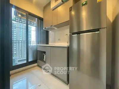 Modern kitchen with sleek cabinetry and stainless steel fridge in high-rise apartment.
