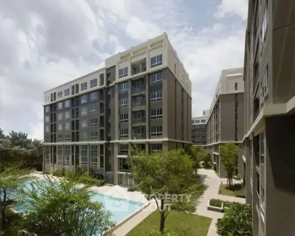 Modern apartment complex with lush greenery and pool view.