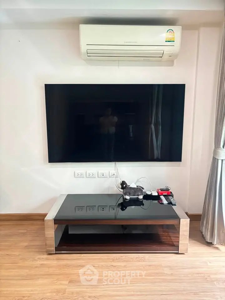 Modern living room with sleek TV setup and air conditioning unit, perfect for comfortable living.