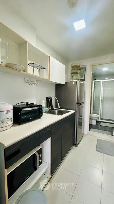 Modern kitchen with sleek appliances and open layout, featuring a microwave and refrigerator.