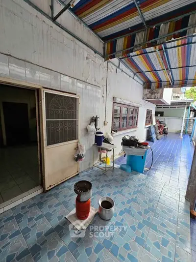 Charming outdoor patio with colorful awning and tiled flooring, perfect for relaxation and gatherings.