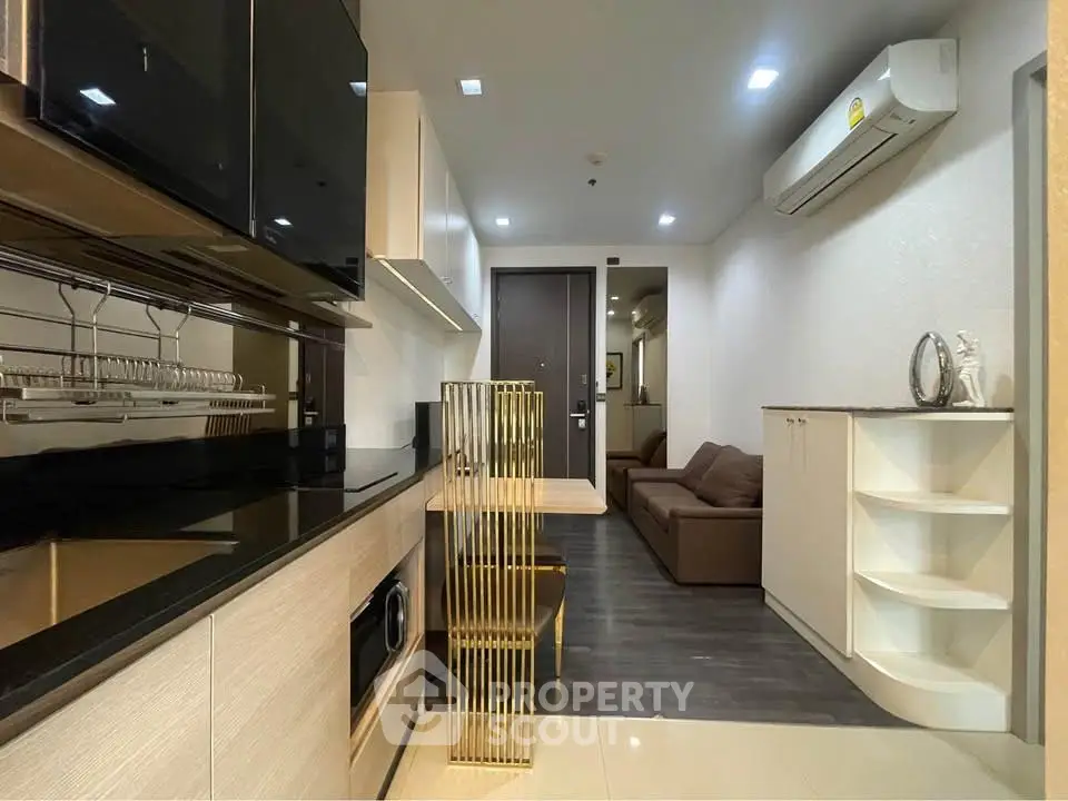 Modern apartment interior with sleek kitchen and cozy living area, featuring contemporary design and efficient use of space.