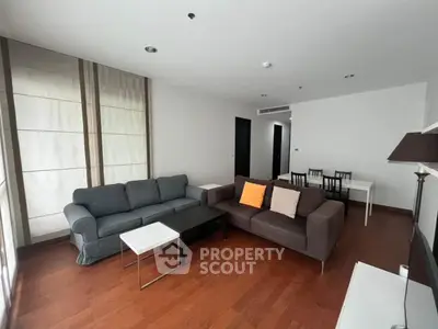 Spacious living room with modern furniture and wooden flooring in a bright apartment.