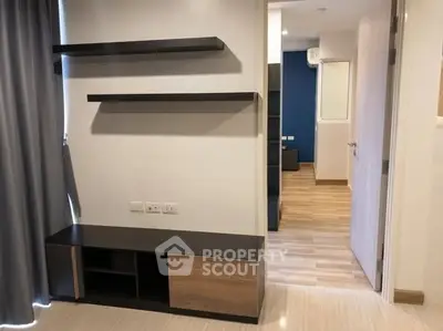 Modern apartment interior with sleek wooden shelves and open doorway, showcasing minimalist design.
