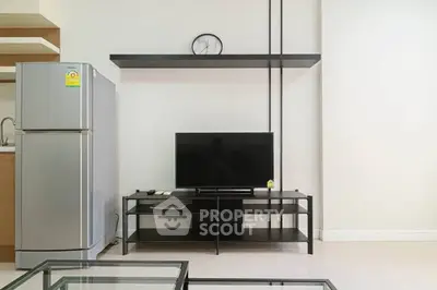 Modern living room with sleek TV stand and stainless steel fridge, perfect for urban living.