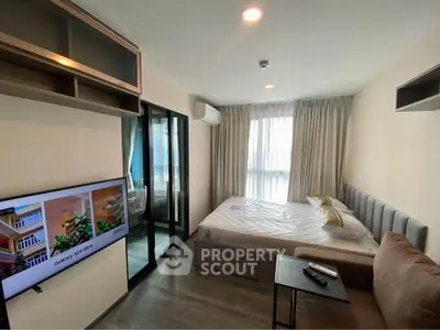 Modern bedroom with cozy bed, TV, and ample natural light from large window.