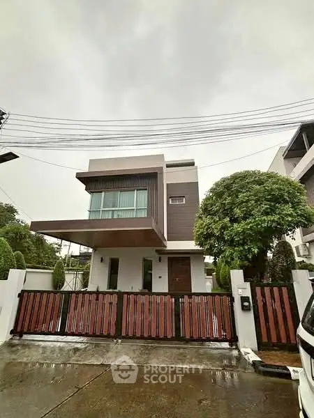 Modern two-story house with sleek design and lush greenery in a suburban neighborhood.
