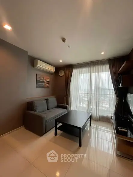 Modern living room with large window and cozy sofa in a high-rise apartment.