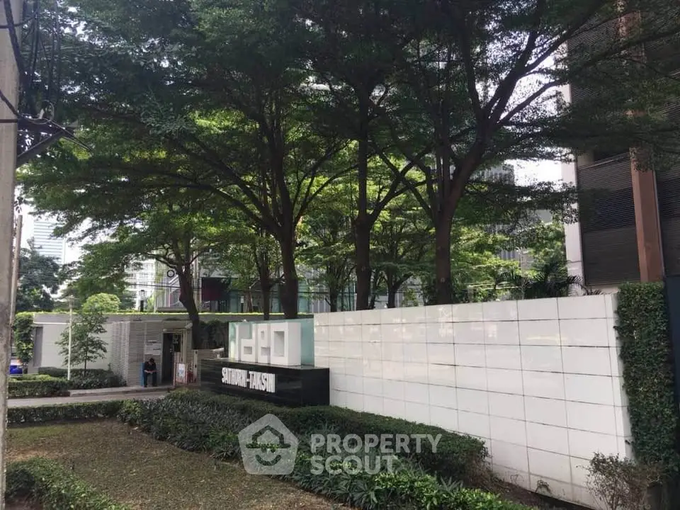 Modern building entrance with lush greenery and stylish signage at Ideo Sathorn Thapra.