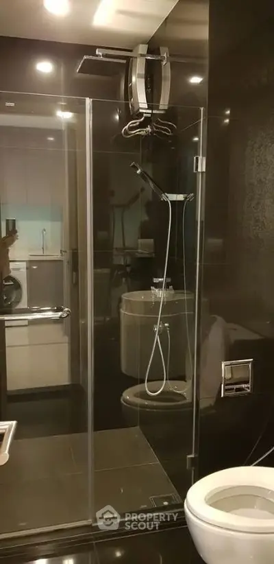 Modern bathroom with glass shower enclosure and sleek black tiles