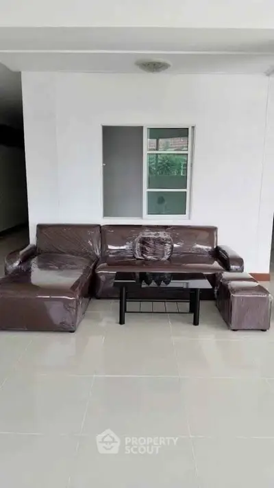 Spacious living room with modern brown sofa set and sleek coffee table.