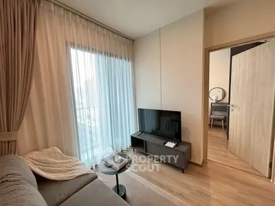 Modern living room with cozy sofa and TV, featuring elegant curtains and wooden flooring.