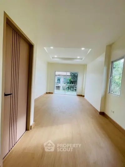 Spacious bright living room with wooden flooring and large windows offering natural light.