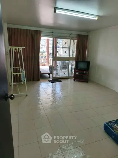 Spacious living room with tiled floor and large windows for natural light.
