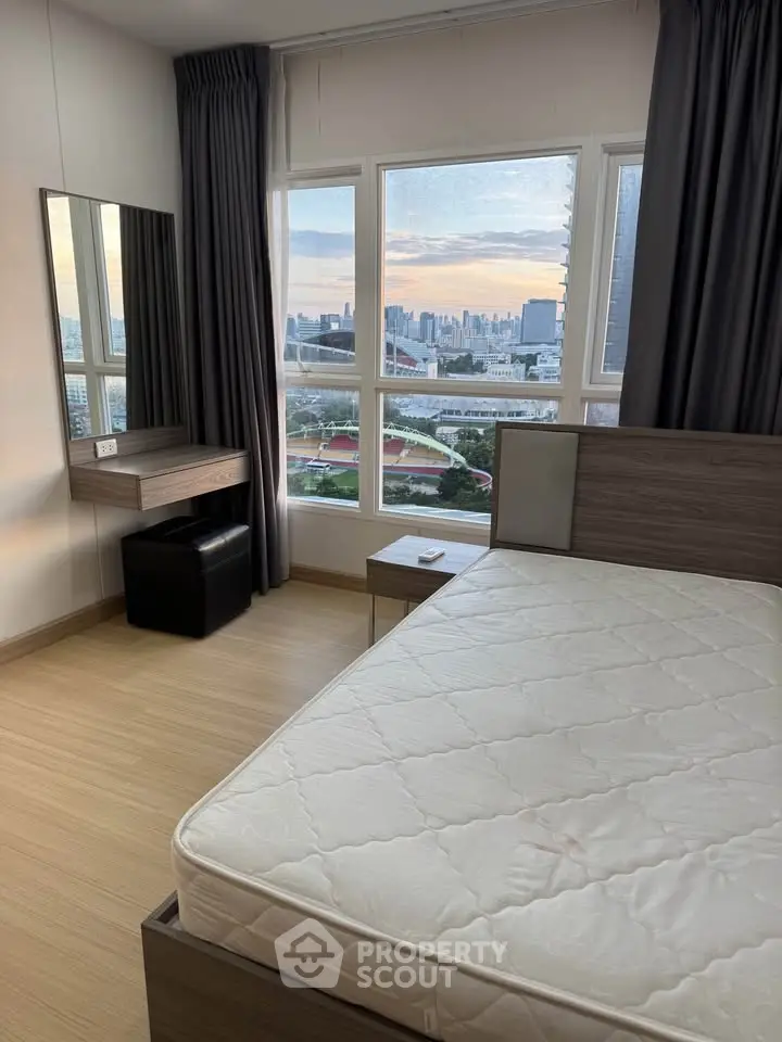 Modern bedroom with city view, featuring large windows and stylish furniture.
