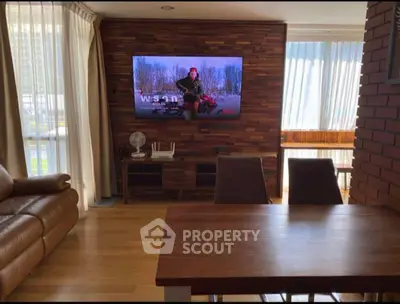 Stylish living room with modern decor and large TV, perfect for relaxation.