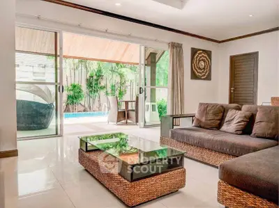 Luxurious living room with pool view and stylish wicker furniture, perfect for relaxation and entertaining.