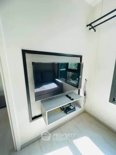 Modern bedroom with wall-mounted TV and sleek shelving in bright, minimalist design.