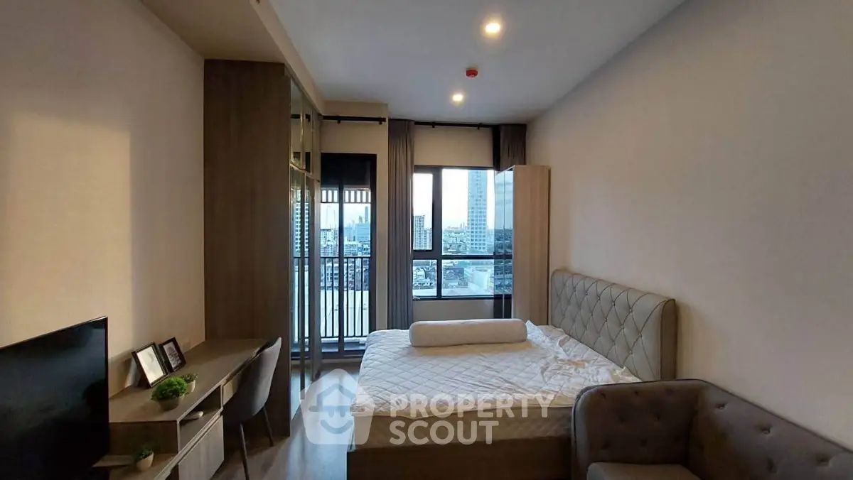 Modern bedroom with city view, featuring stylish furniture and natural light.