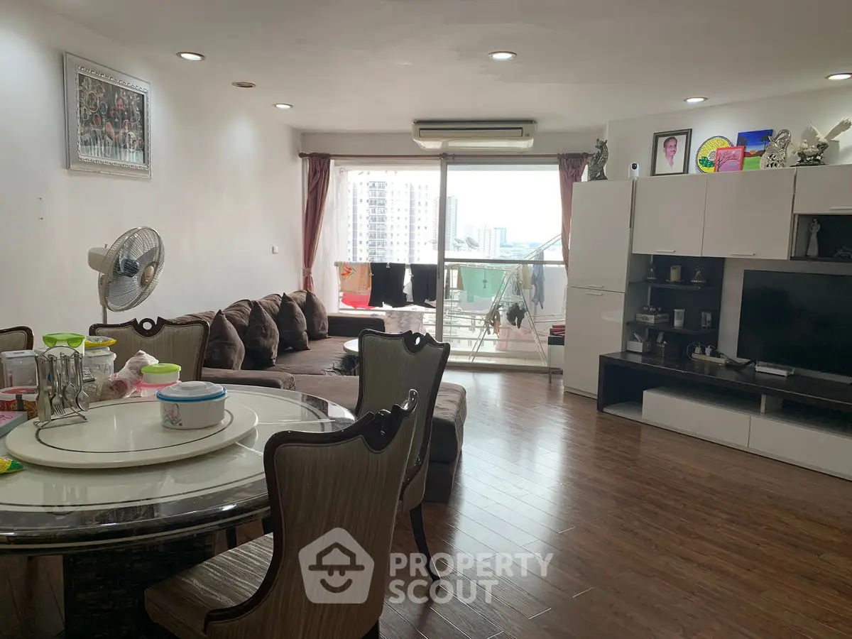 Spacious living room with modern decor and balcony view in high-rise apartment.