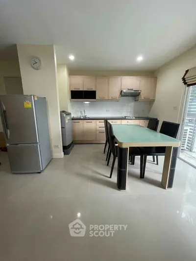 Modern kitchen with dining area, featuring sleek cabinetry and stainless steel appliances.